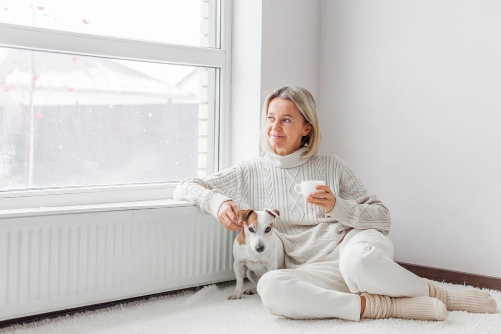 relaxed,,serene,adult,woman,near,radiator,drinking,cup,of,coffee