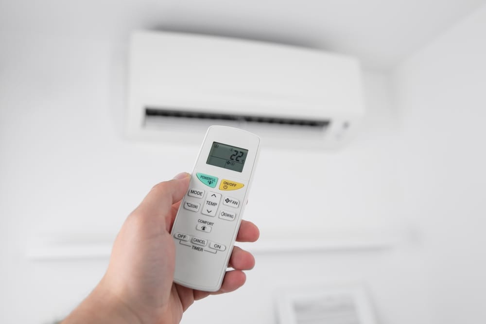 omme tenant une télécommande de climatiseur moderne.